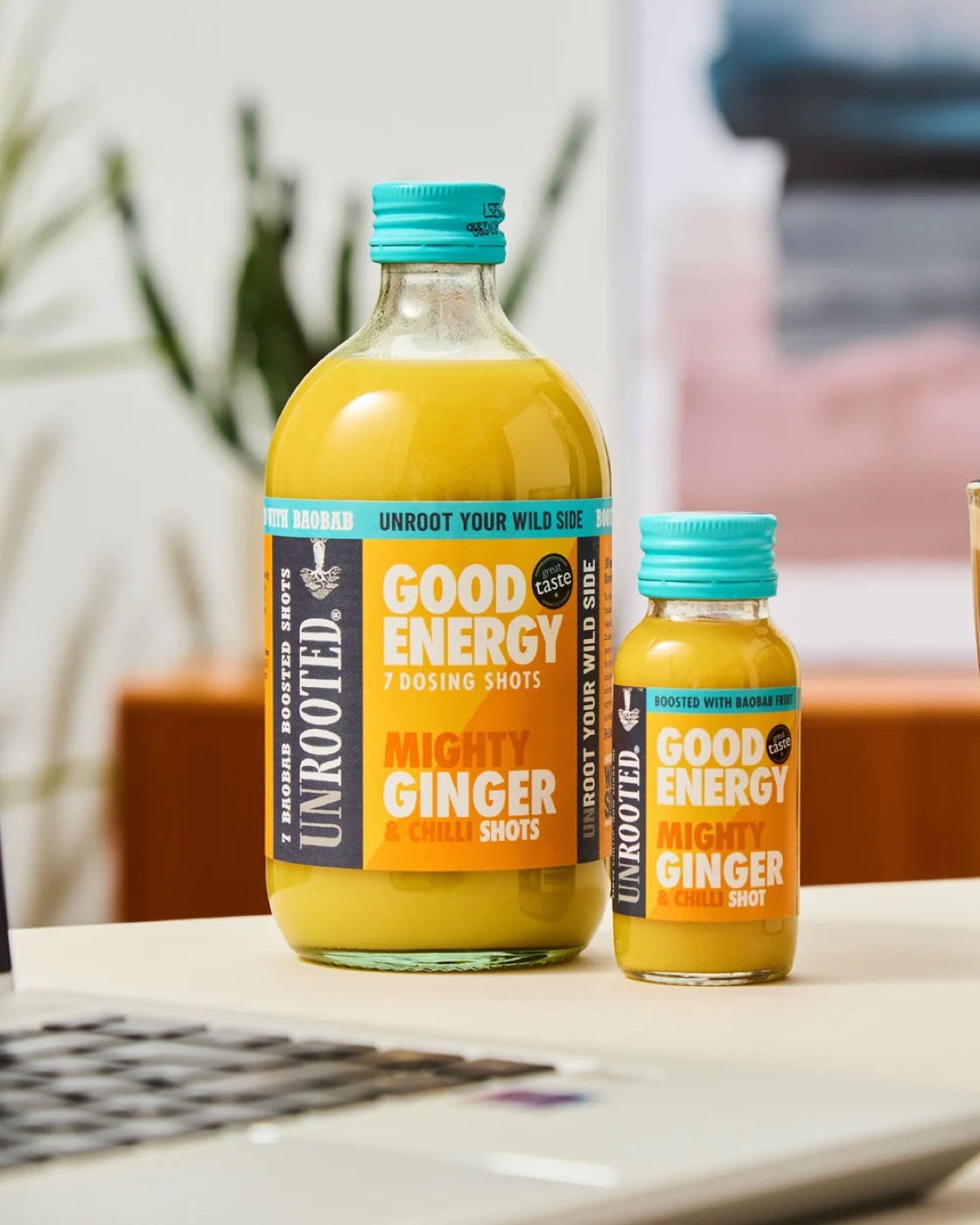 The UNROOTED 420ml dosing bottle beside the 60ml Mighty Ginger shot bottle.